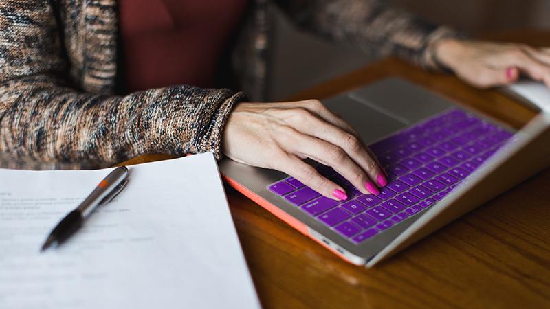 Purple laptop with hands typing